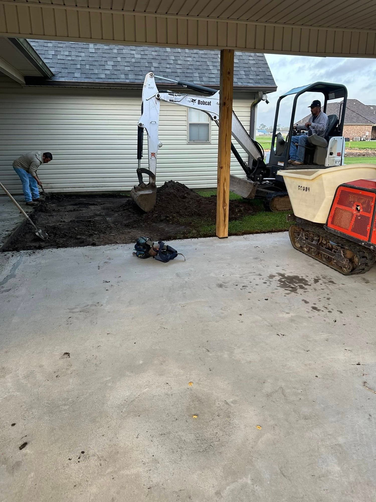 Concrete pad grading and finishing with Bobcat — Foret Construction crew