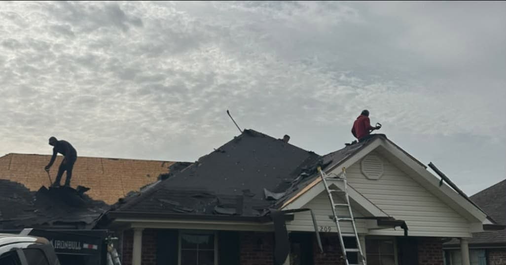 Foret Construction crew tearing off old shingles during a roof replacement