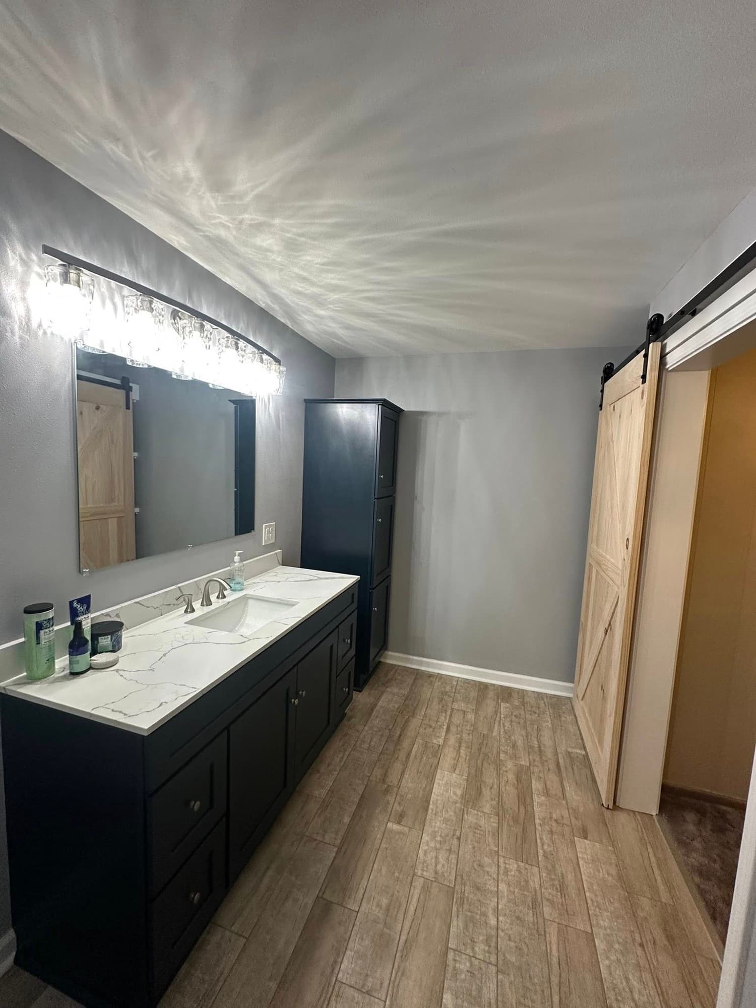 Modern bathroom remodel with marble vanity and barn door — Foret Construction, Lafourche Parish